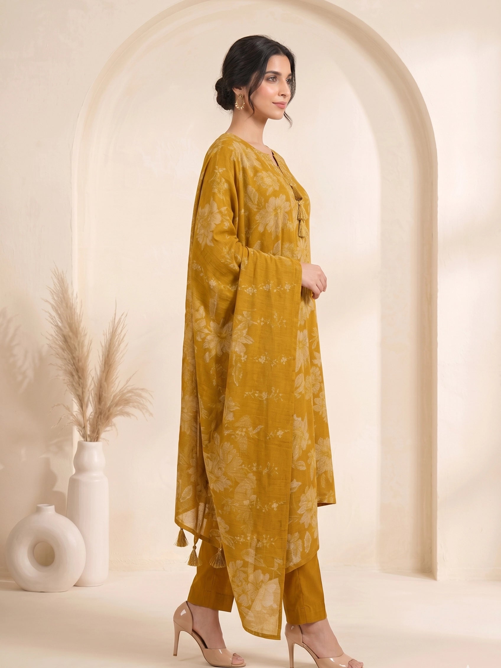 Woman wearing a mustard yellow floral print cotton kurti set with a dupatta and beige heels.