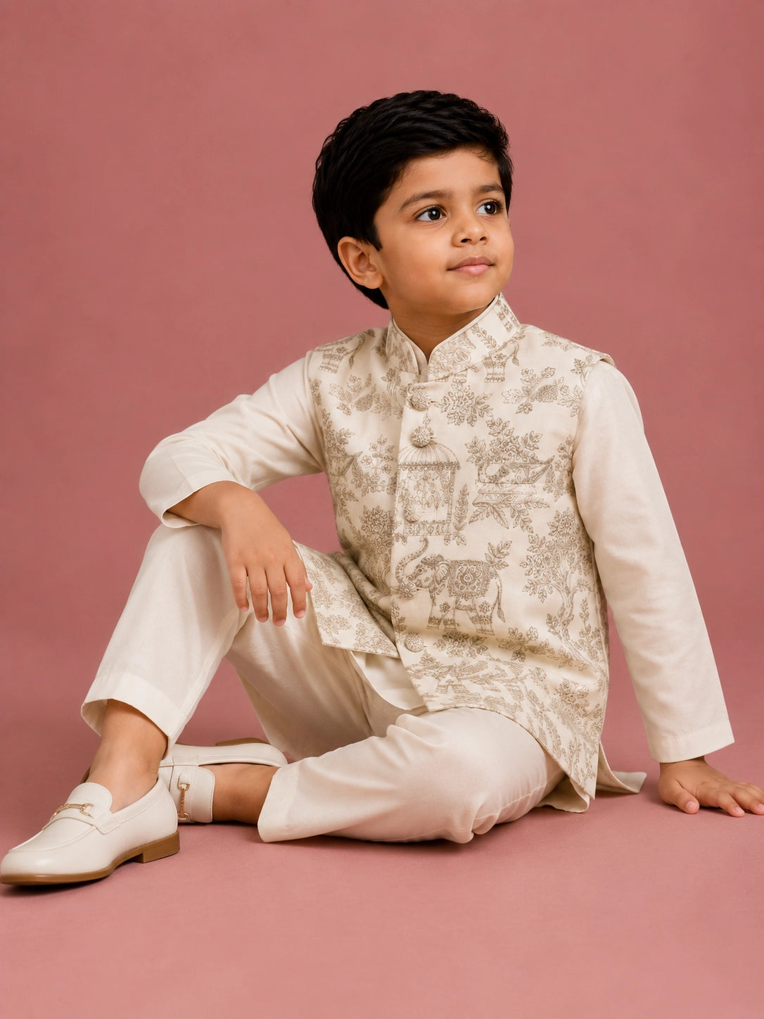 Young boy wearing an off-white embroidered bandhgala waistcoat over a kurta pajama.