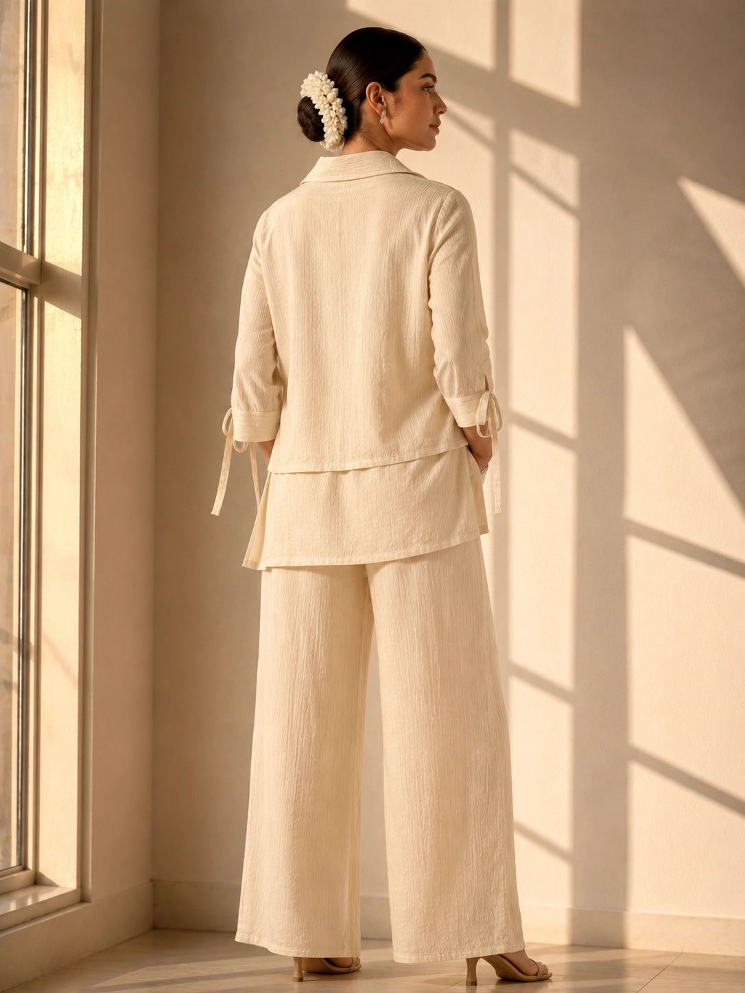 Woman wearing an elegant beige embroidered kurti with wide-leg palazzo pants.