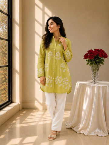 Woman in pista green embroidered tunic kurti and white trousers, smiling.