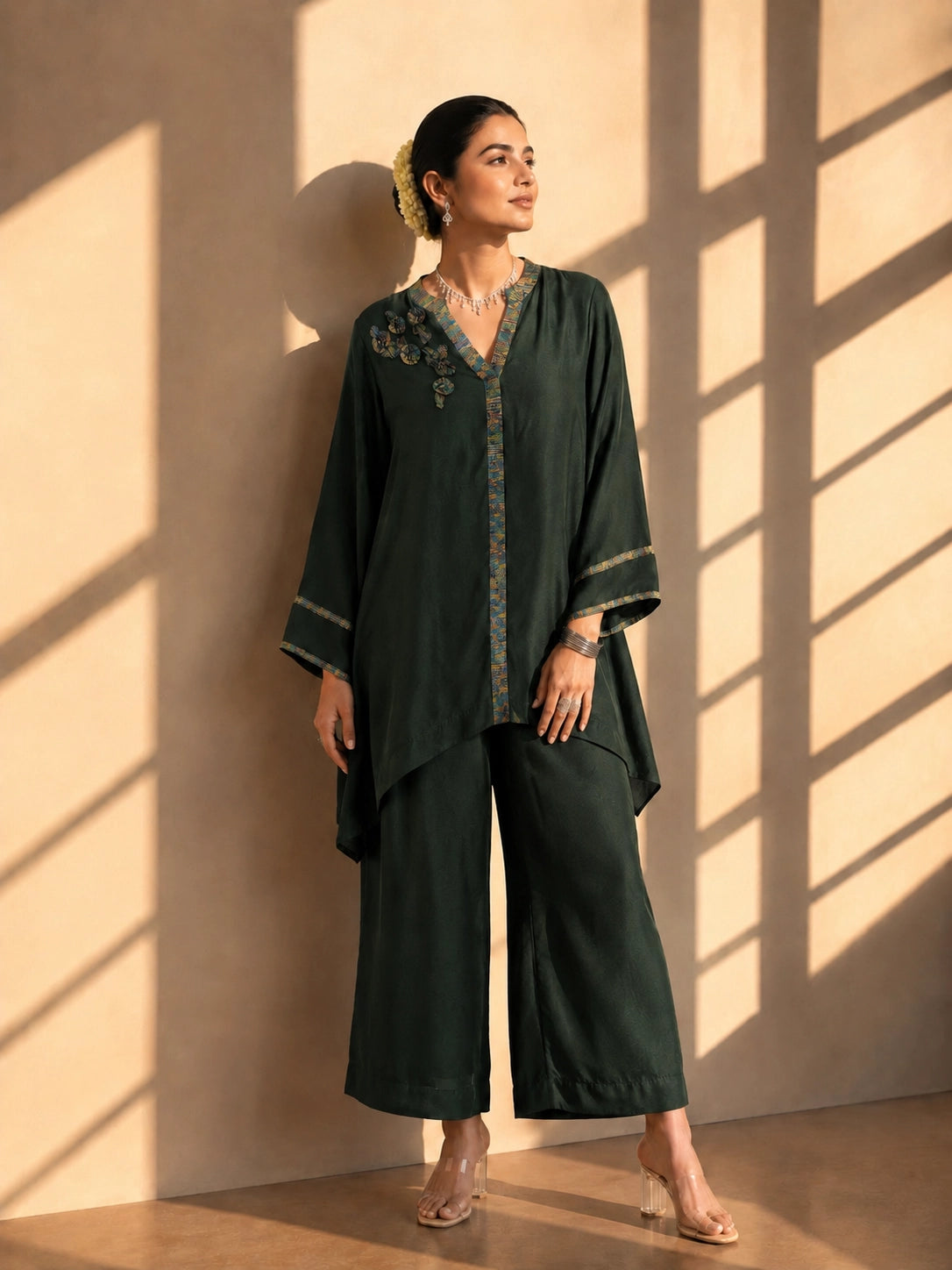 Model wearing a dark green asymmetric tunic with wide-leg pants and floral embroidery.