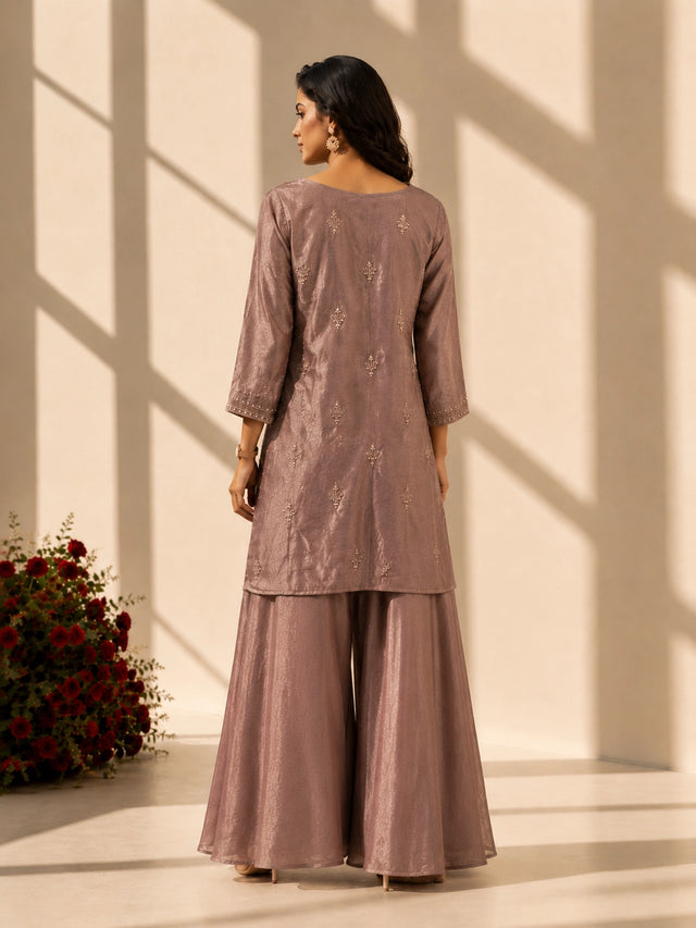 Woman in an elegant onion-colored embroidered kurti set with palazzo pants and matching scarf.
