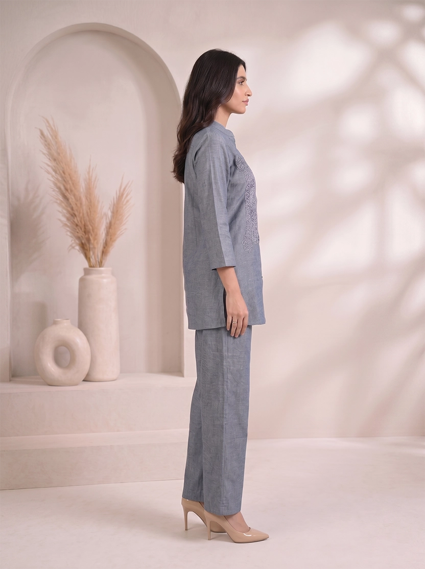 Woman wearing a blue cotton co-ord set with embroidered details on the top and straight-leg pants.