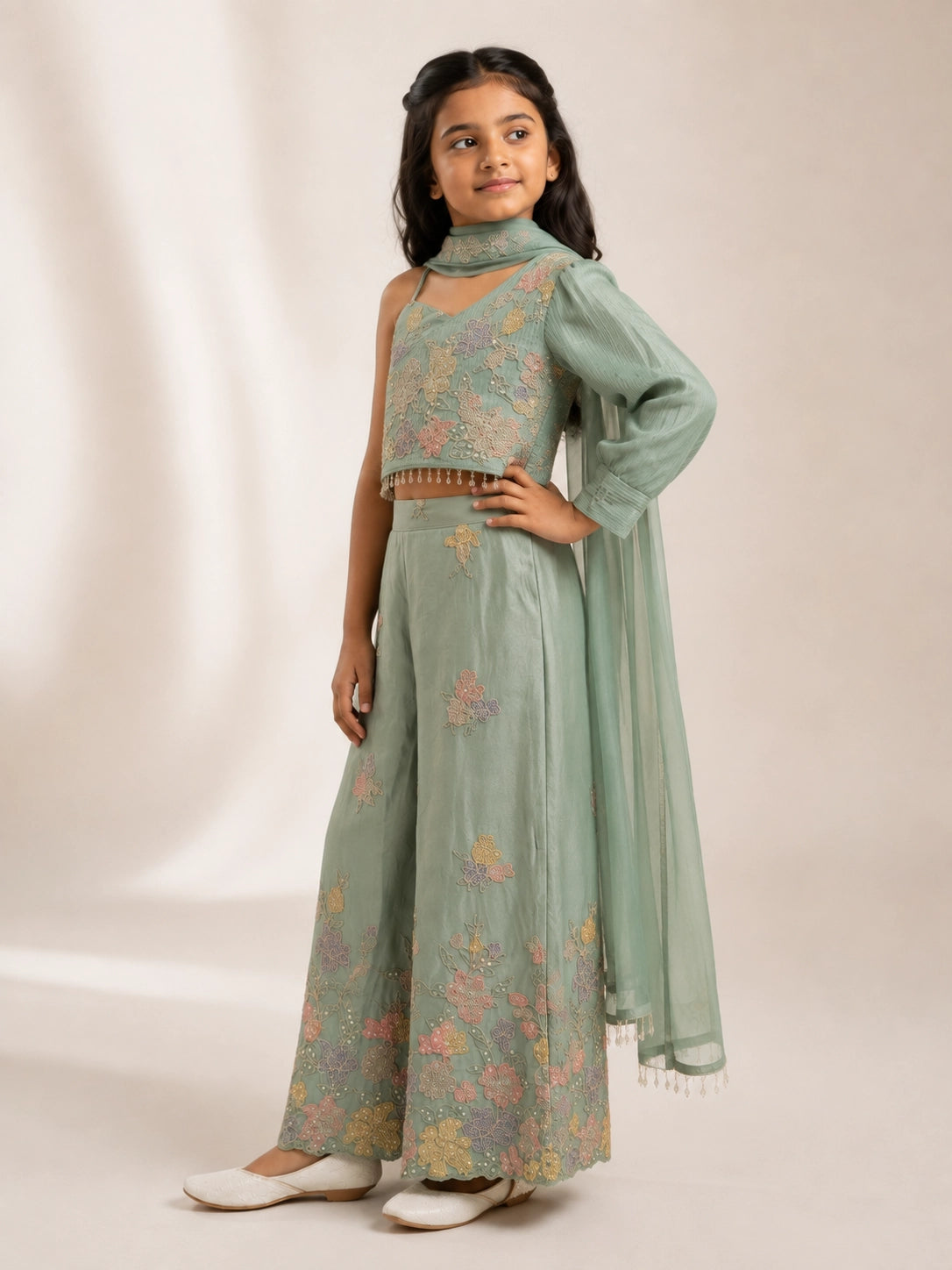 Young girl wearing a green embroidered one-shoulder palazzo set with a matching dupatta.