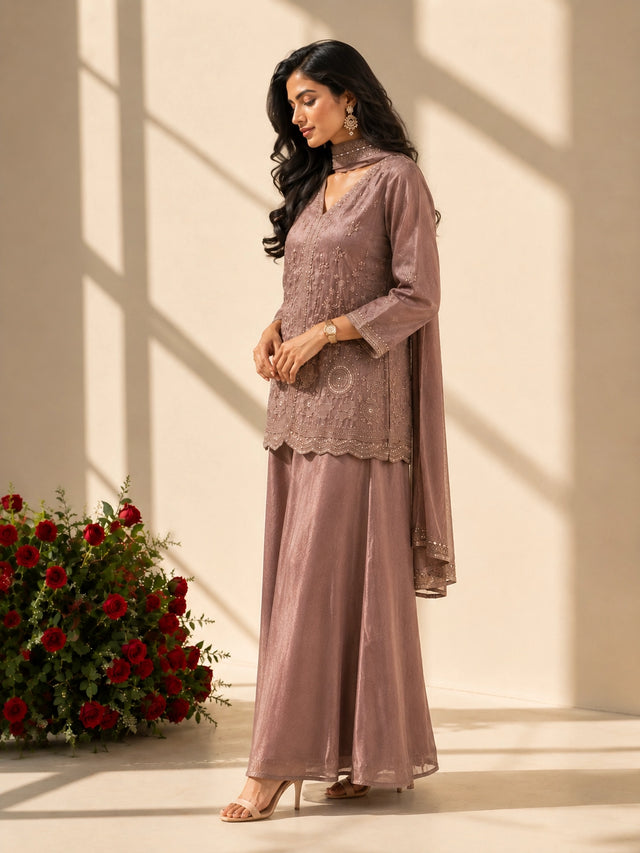 Woman in an elegant onion-colored embroidered kurti set with palazzo pants and matching scarf.