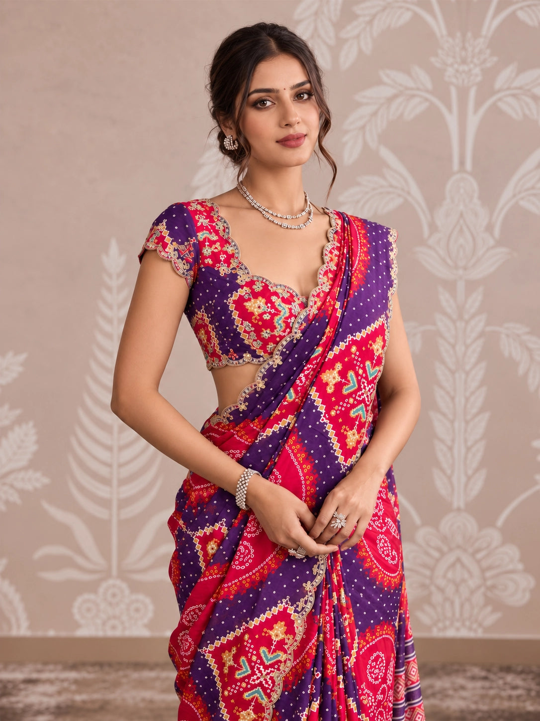 Woman in vibrant purple and pink printed saree with intricate patterns and scalloped border.