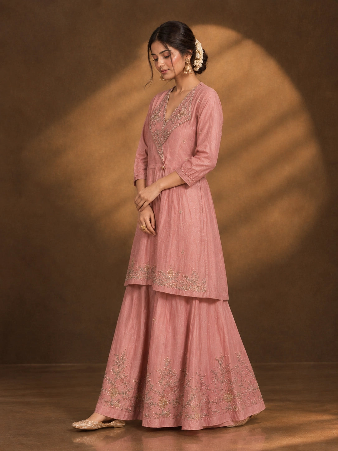 Woman in an elegant pink angrakha kurti and sharara set with intricate gold embroidery.