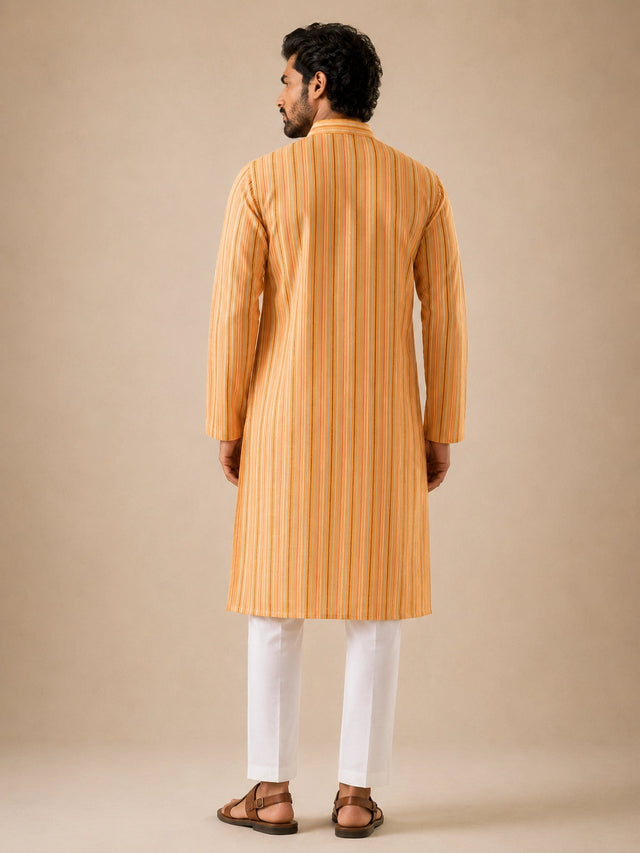 Man in a yellow striped kurta and white pajama, standing with hands behind back.