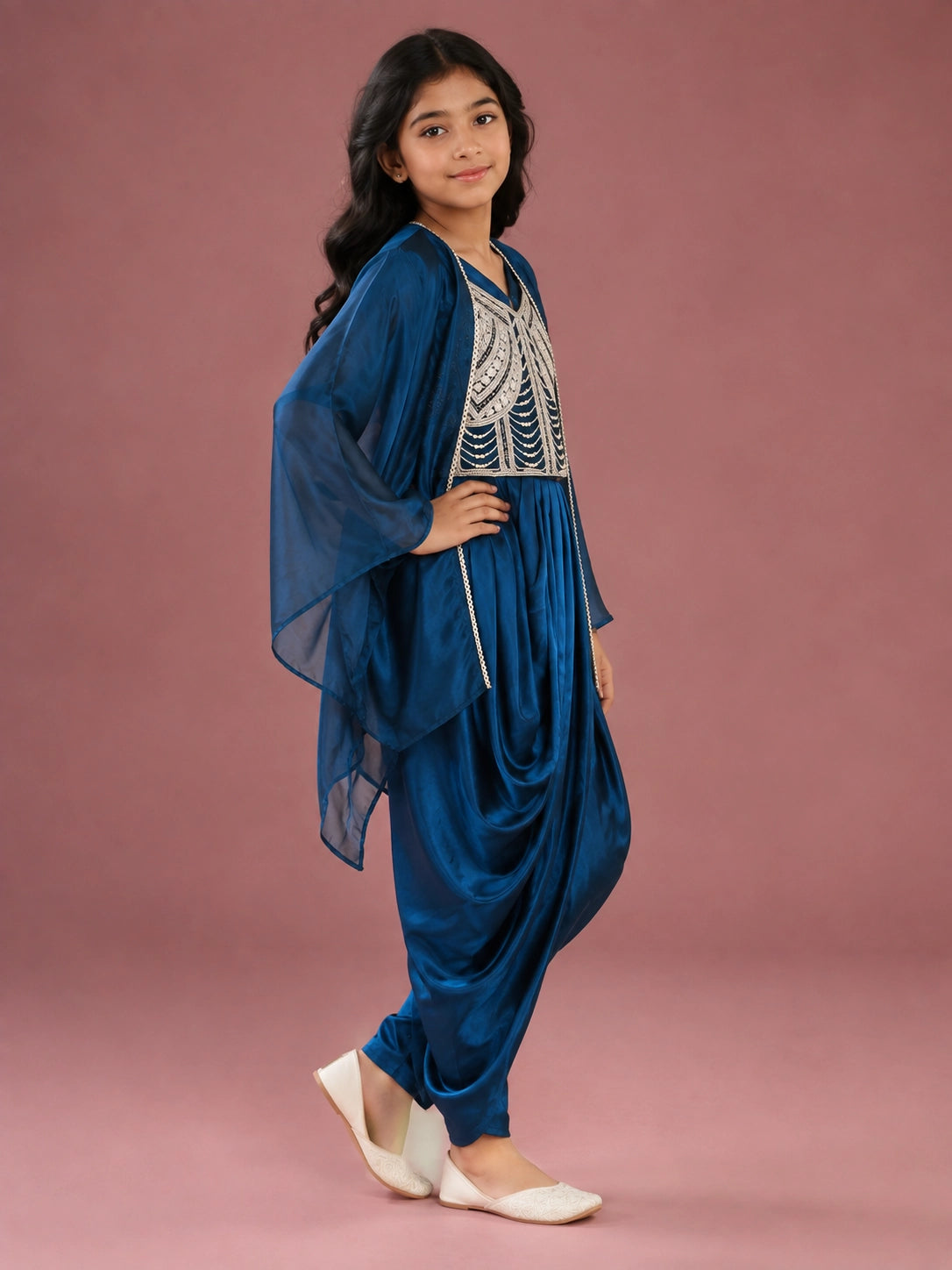 Young girl wearing a vibrant blue dhoti set with an embellished top and sheer jacket.