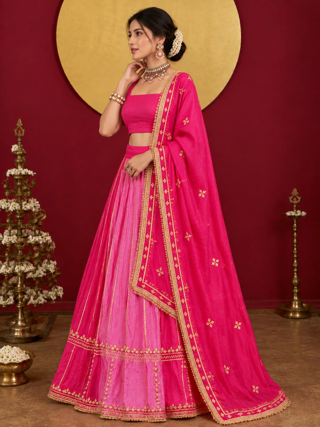 Woman in a vibrant rani pink ombre lehenga choli with gold embroidery.