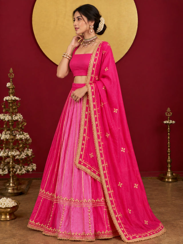 Woman in a vibrant rani pink ombre lehenga choli with gold embroidery.