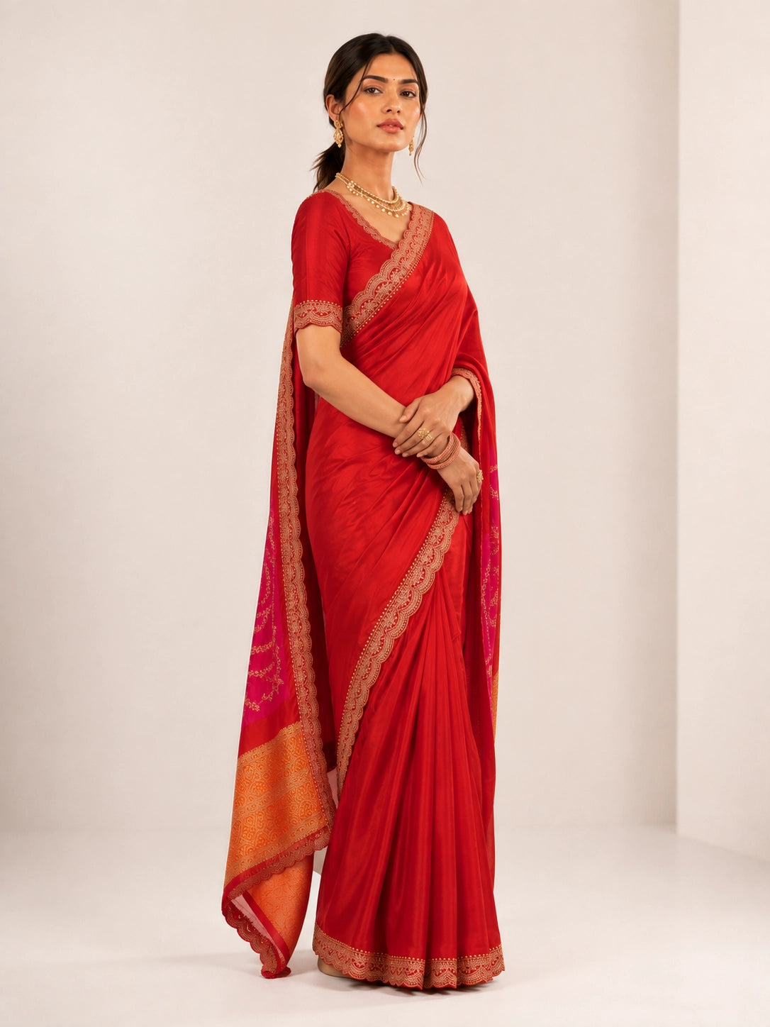 Woman wearing a luxurious red saree with golden embroidered borders and a vibrant pallu.