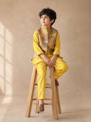 Young boy wearing a vibrant yellow kurta pajama and a colorful patterned Nehru jacket.