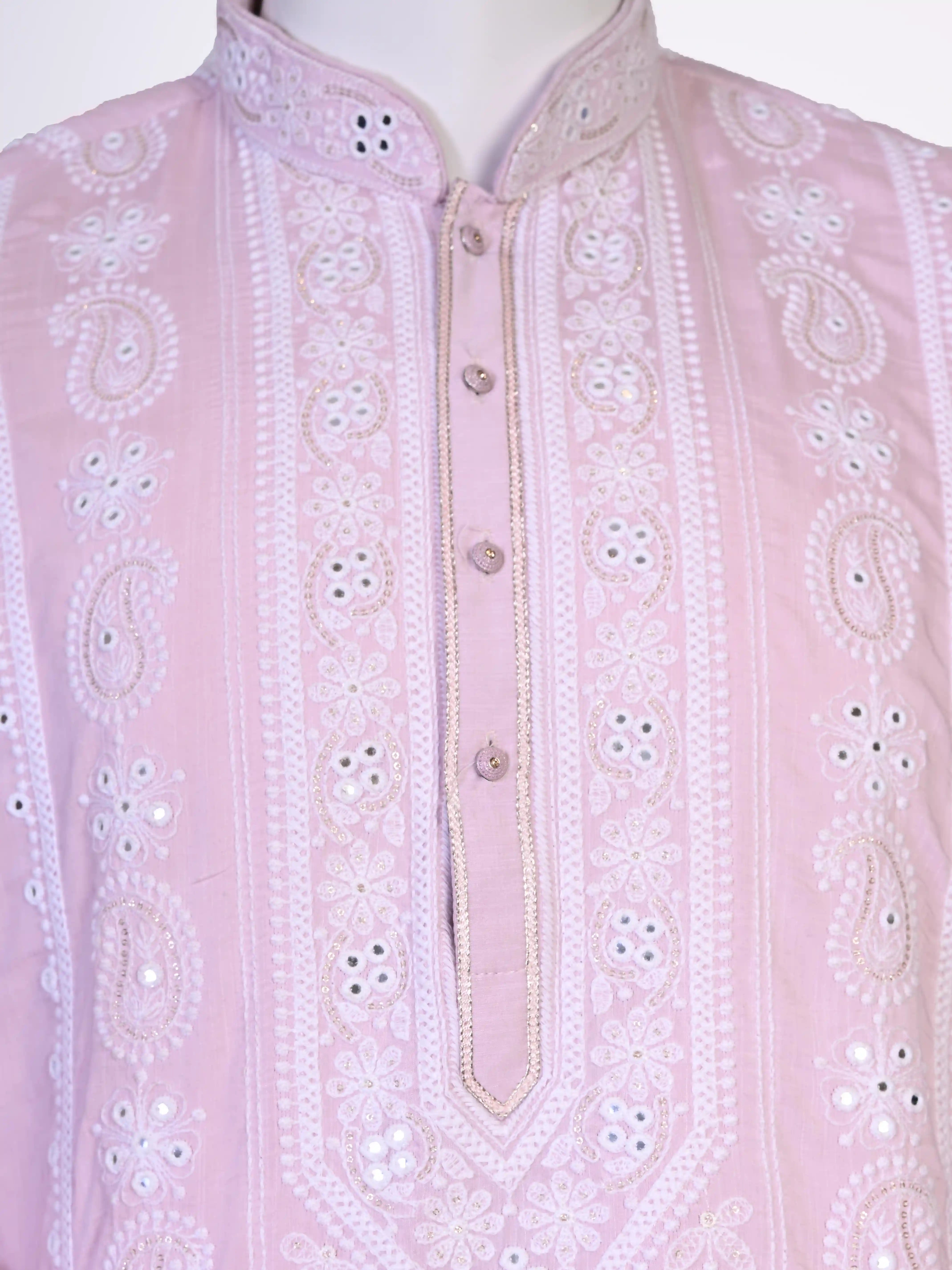 Man wearing a pink chikankari kurta with white churidar pants and brown embellished juttis.