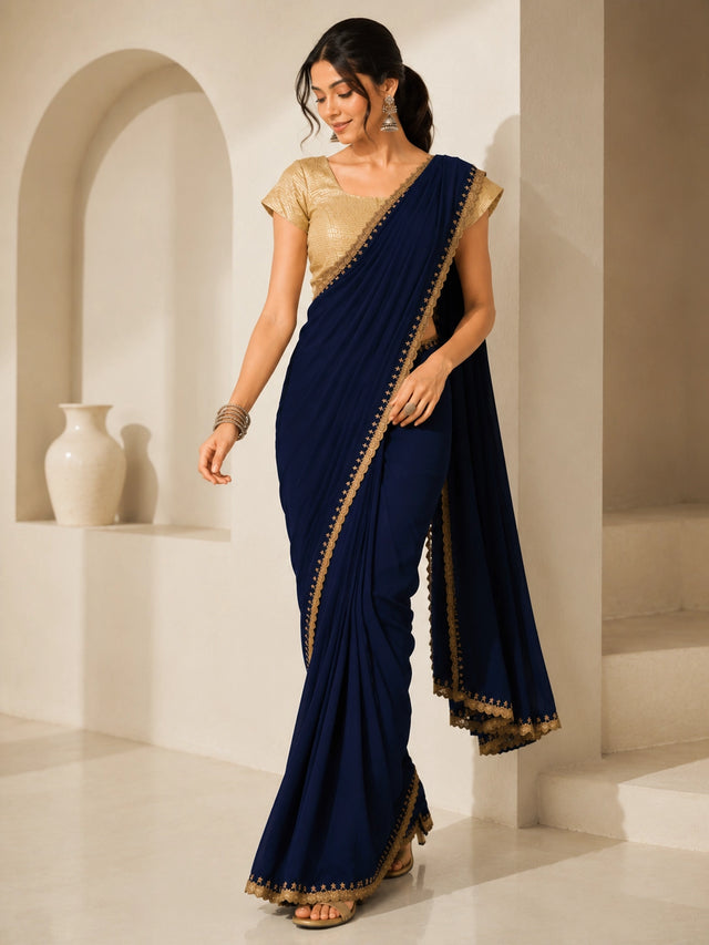 Woman wearing a navy blue saree with gold embroidered borders and a gold blouse.