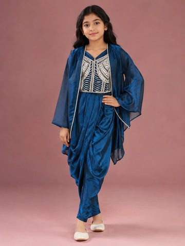 Young girl wearing a vibrant blue dhoti set with an embellished top and sheer jacket.