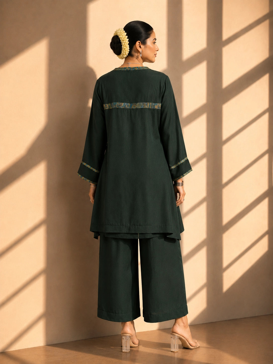 Model wearing a dark green asymmetric tunic with wide-leg pants and floral embroidery.