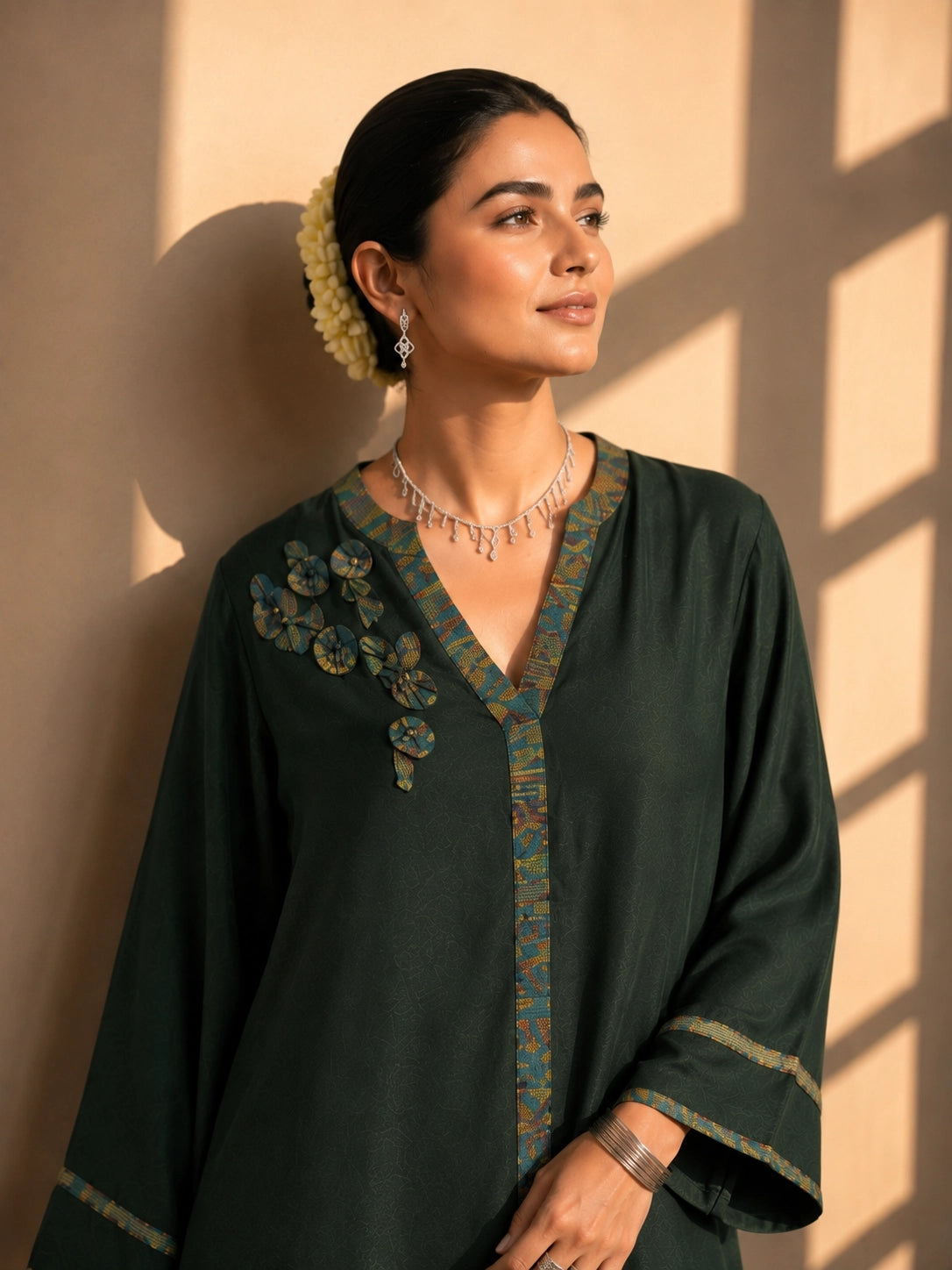 Model wearing a dark green asymmetric tunic with wide-leg pants and floral embroidery.