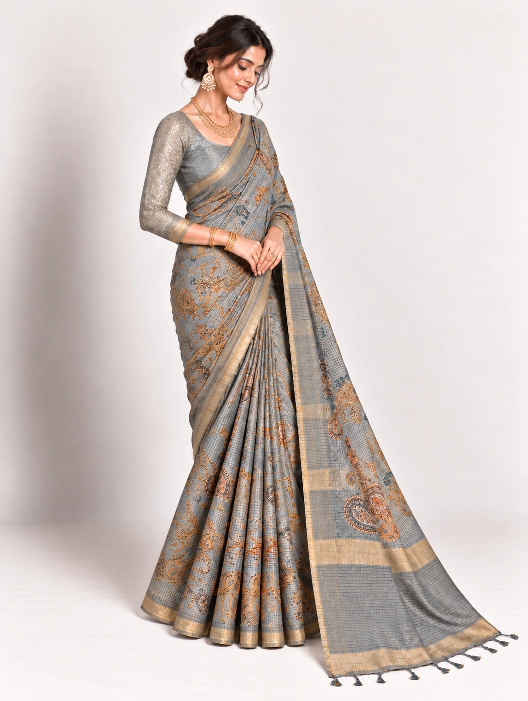 Woman in an elegant lavender grey saree with gold border and intricate paisley patterns.