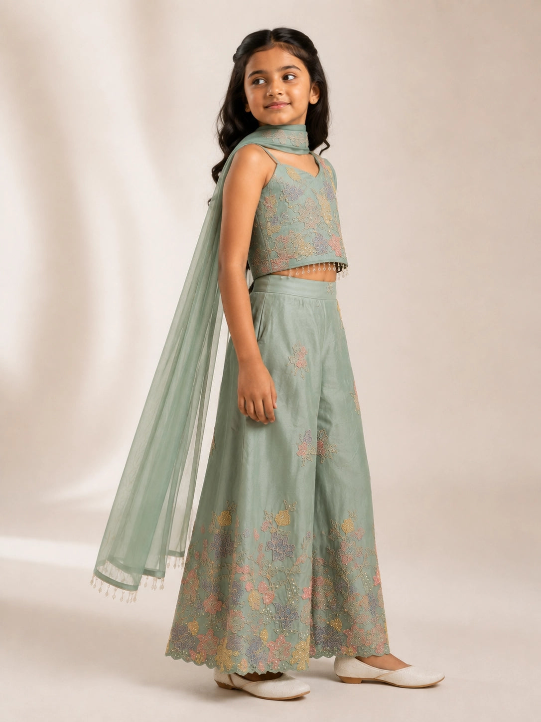 Young girl wearing a green embroidered one-shoulder palazzo set with a matching dupatta.