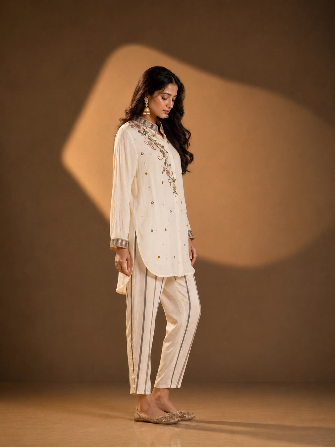 Woman wearing an elegant cream embroidered button-down kurti with striped collar and cuffs.