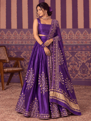 Woman in a vibrant purple embroidered lehenga choli set with gold patterns.