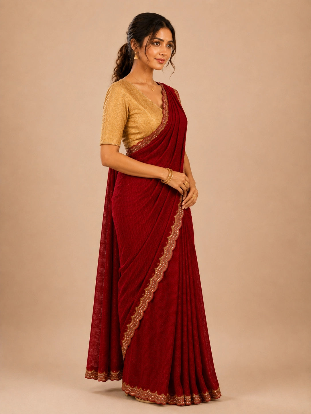 Woman in elegant red pleated saree with embellished border and golden blouse.