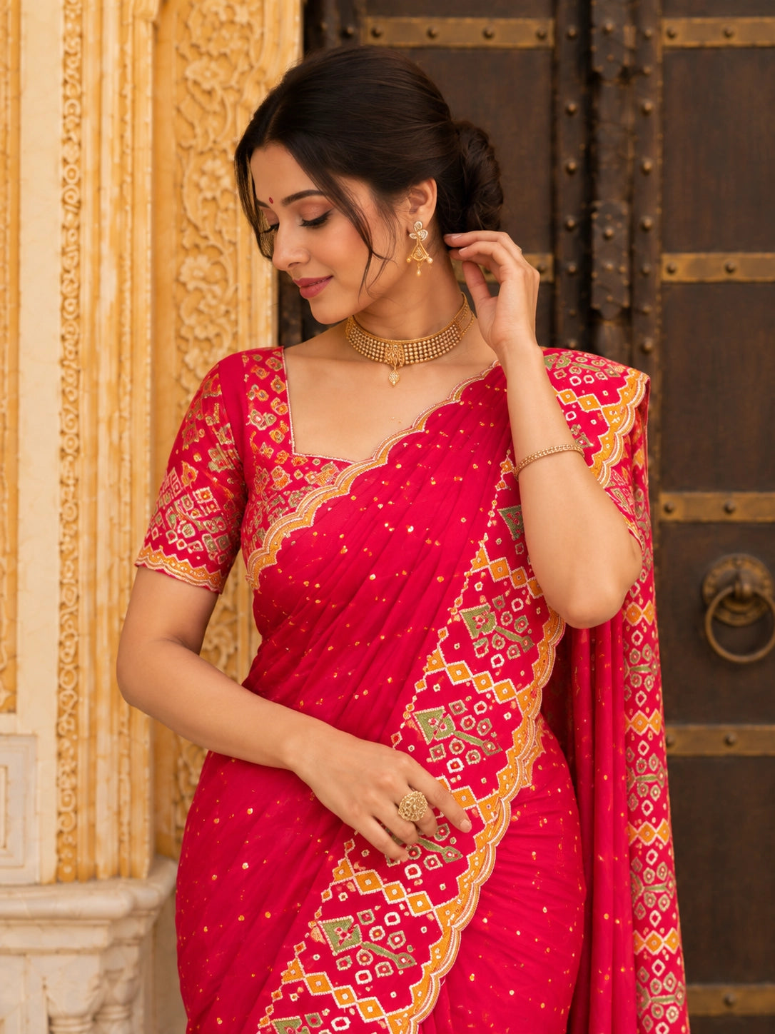 Woman in a vibrant red  saree with golden embroidery sitting on steps.