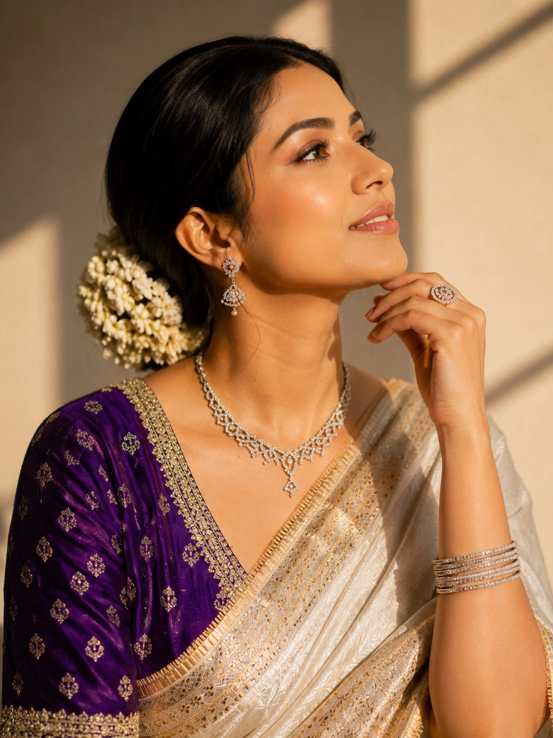 Woman in luxurious cream saree with gold border and embroidered purple blouse.
