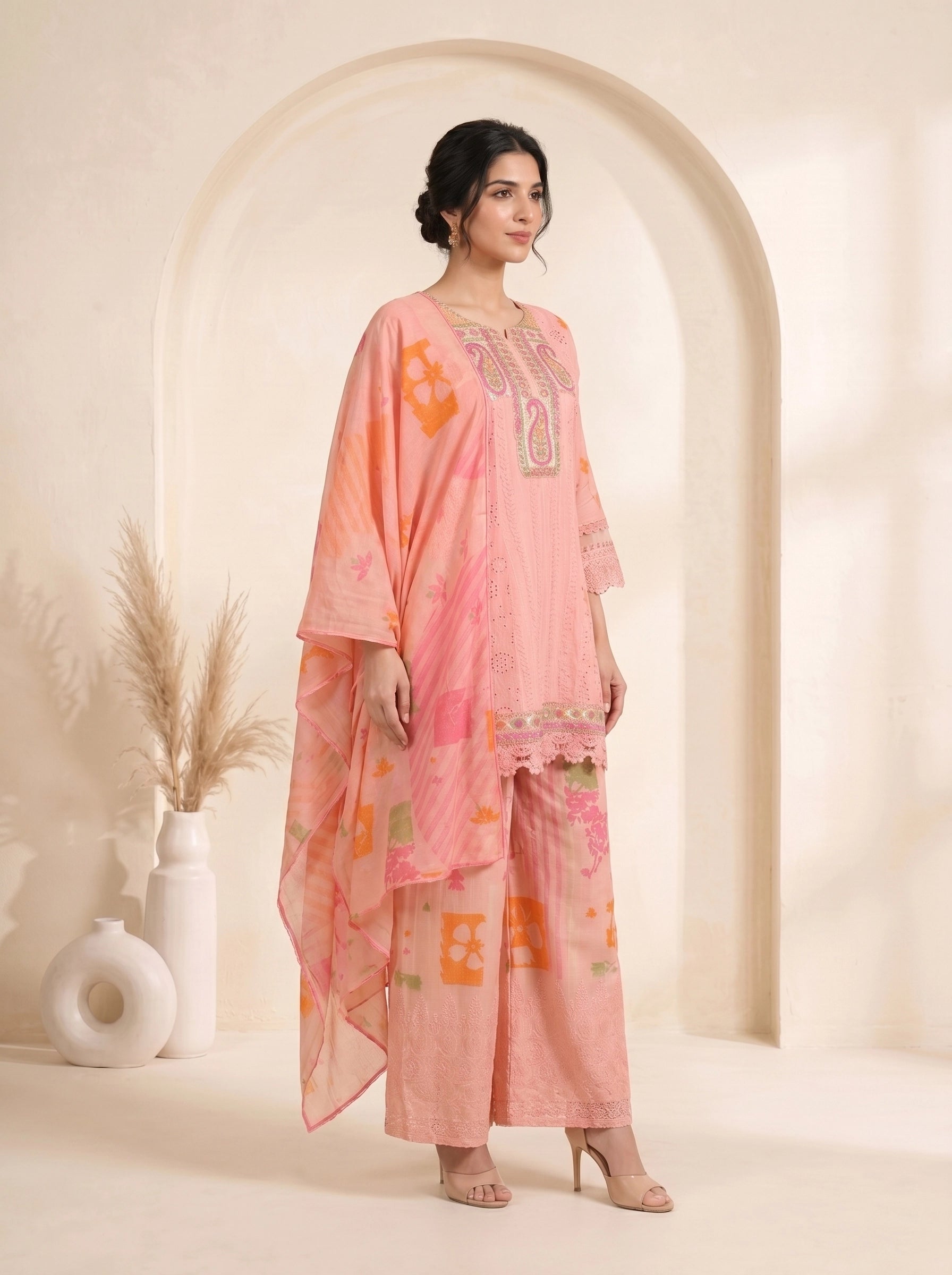 Woman wearing a pink printed cotton kurti set with palazzo pants and a dupatta, featuring eyelet details and block prints.