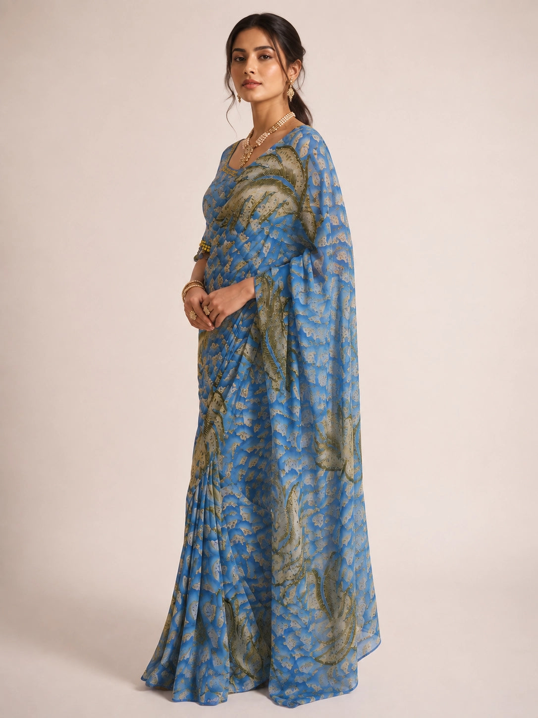 Woman wearing a sky blue  printed saree with olive feather patterns.