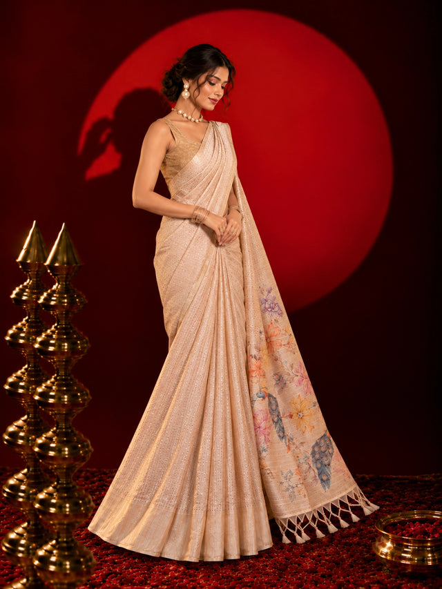 Woman in an elegant beige saree with floral and peacock pallu design.