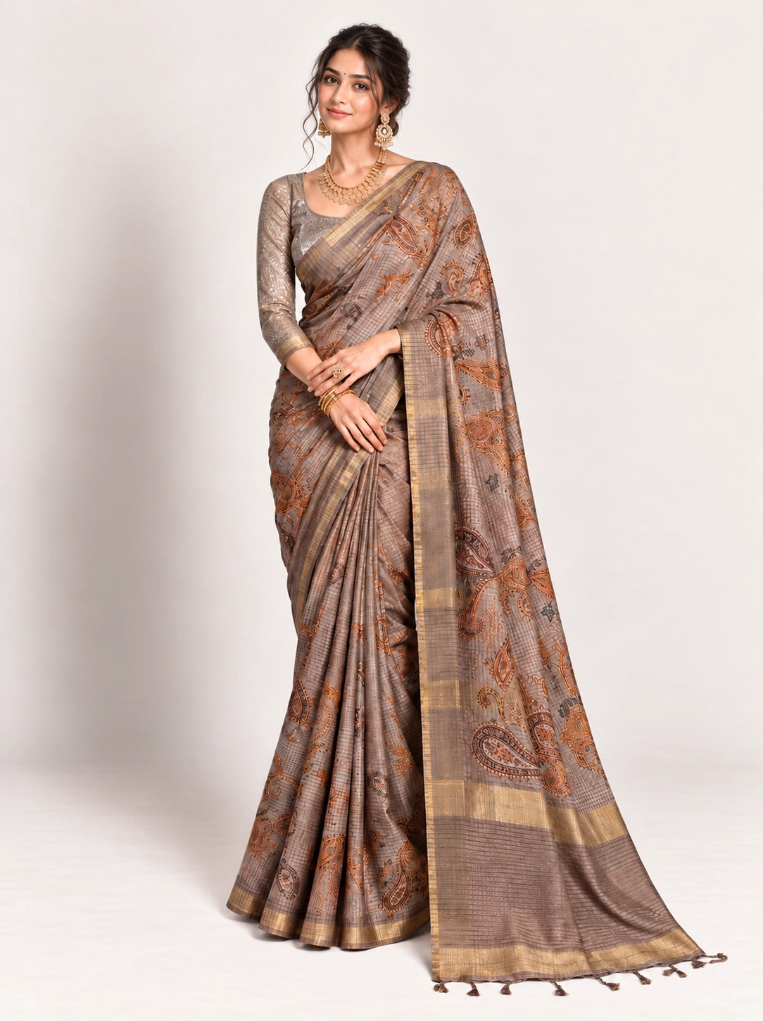 Woman in an elegant lavender grey saree with gold border and intricate paisley patterns.