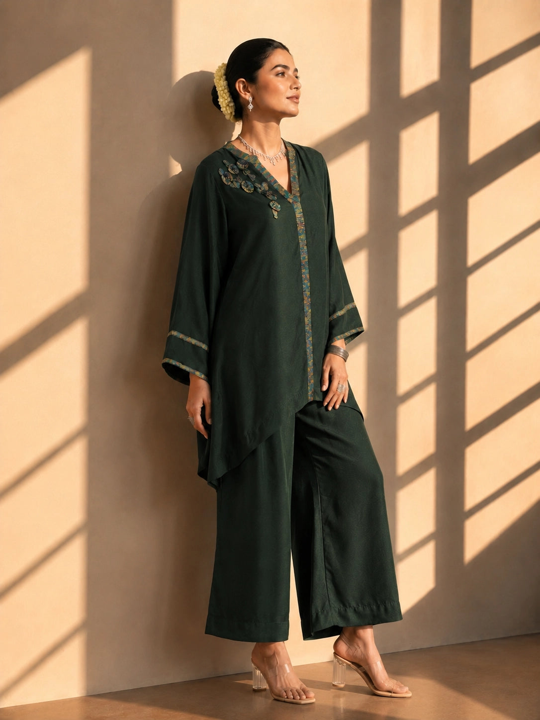 Model wearing a dark green asymmetric tunic with wide-leg pants and floral embroidery.