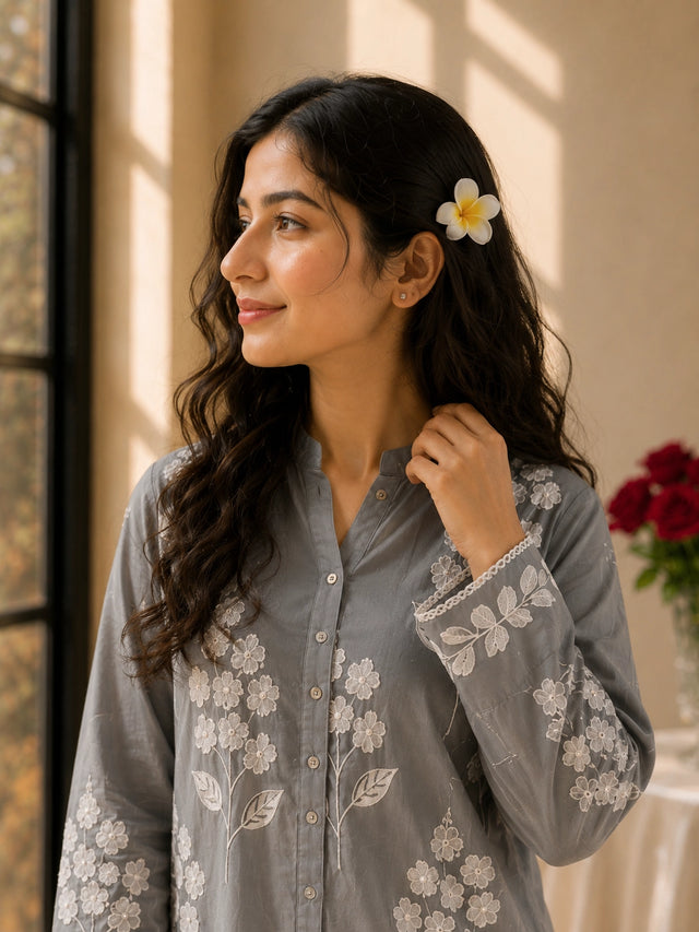 Woman wearing a sky blue embroidered tunic with white pants and sandals.