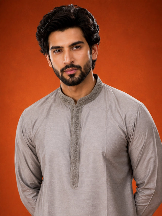 Man in elegant grey kurta with embroidered collar and white pajama set.