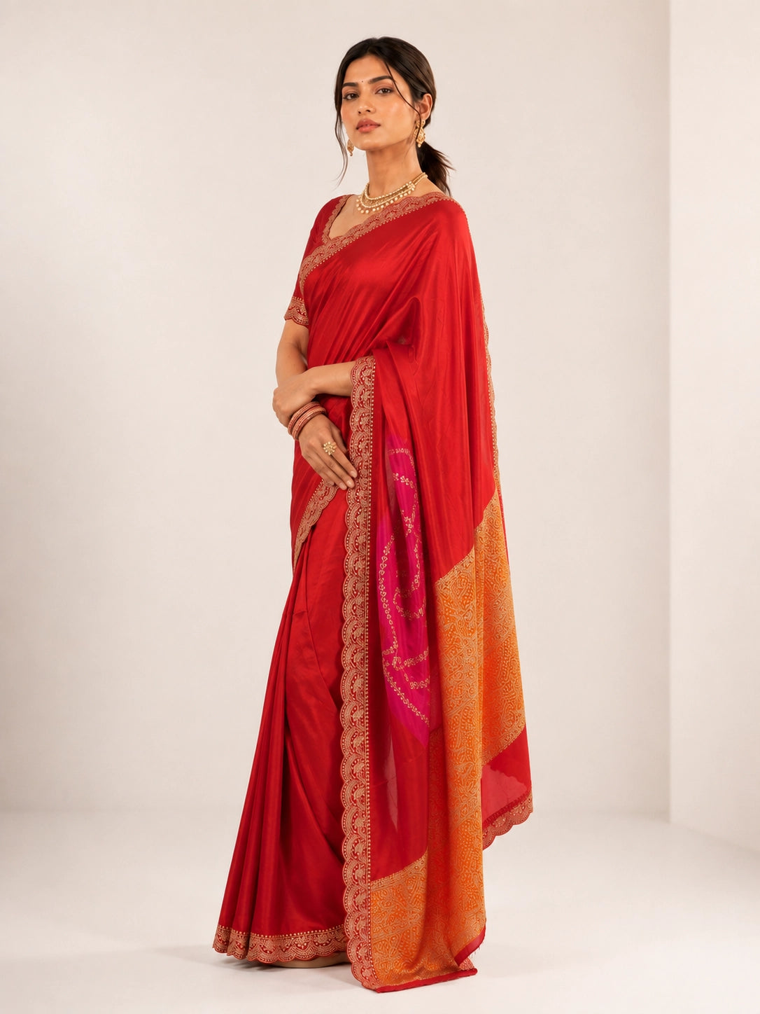Woman wearing a luxurious red saree with golden embroidered borders and a vibrant pallu.