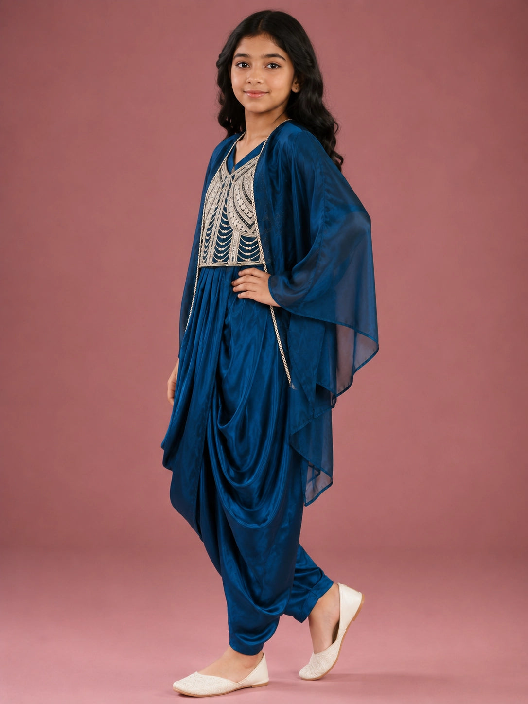 Young girl wearing a vibrant blue dhoti set with an embellished top and sheer jacket.
