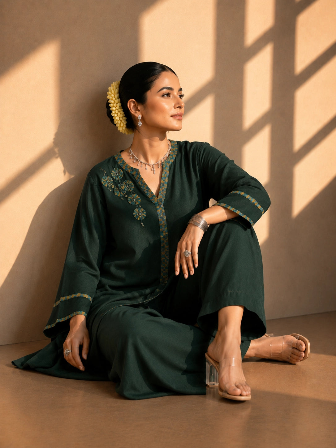 Model wearing a dark green asymmetric tunic with wide-leg pants and floral embroidery.