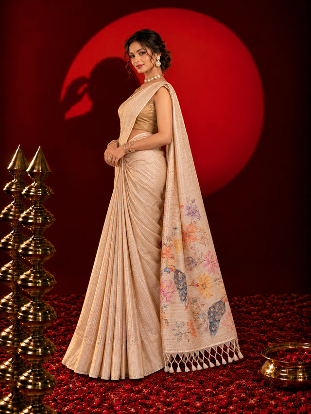Woman in an elegant beige saree with floral and peacock pallu design.
