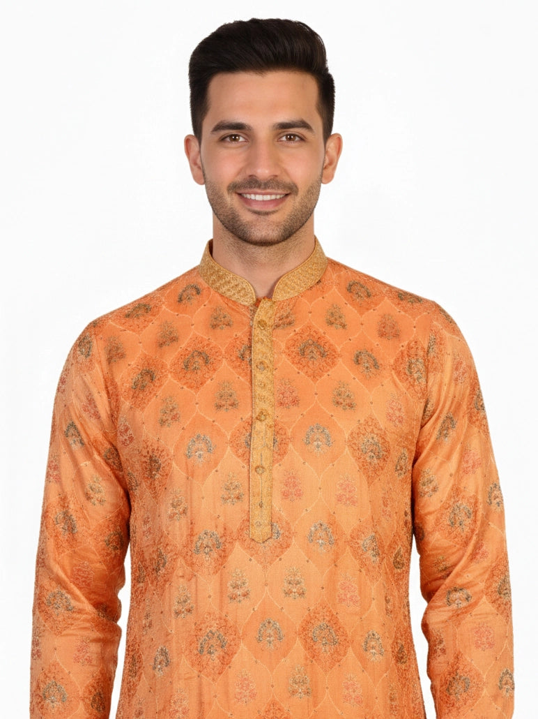 Man wearing an orange embroidered Kurta Pajama with cream pants and brown shoes, showcasing intricate patterns.