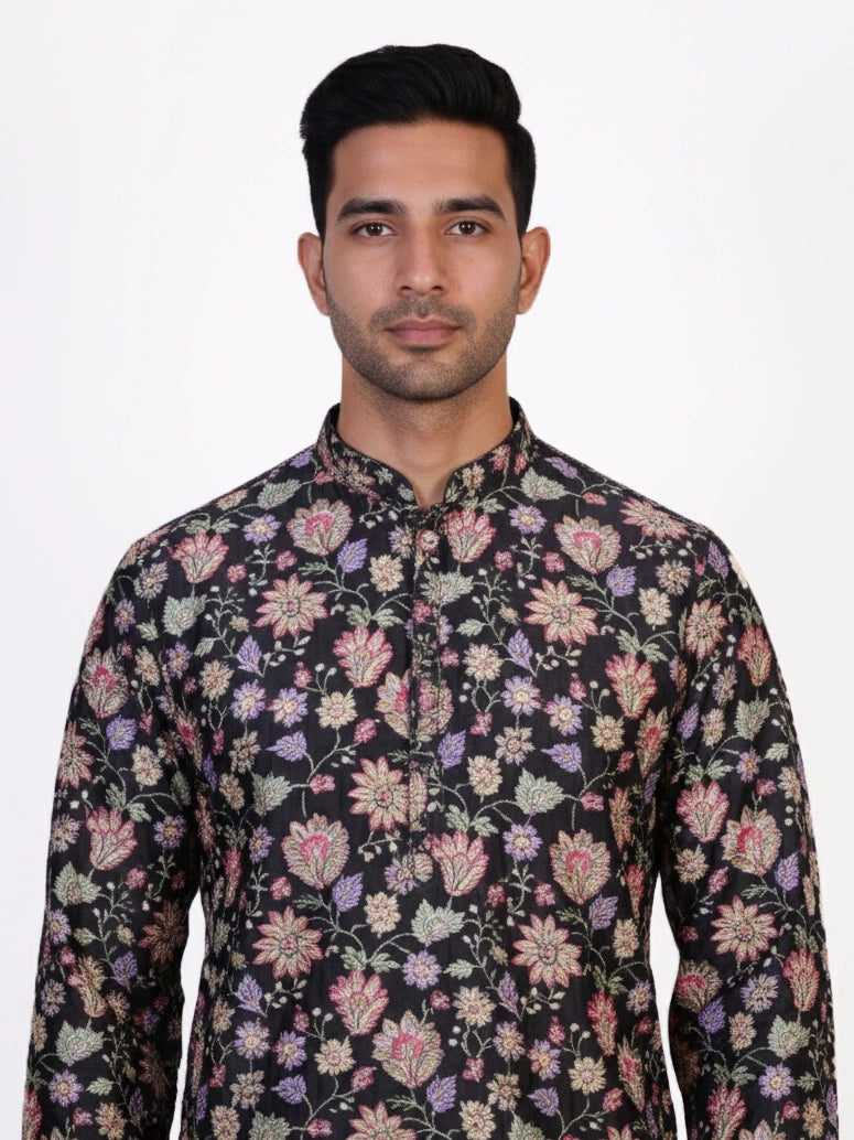 Man wearing a dark multi-color floral print kurta and white churidar pants, traditional ethnic wear.