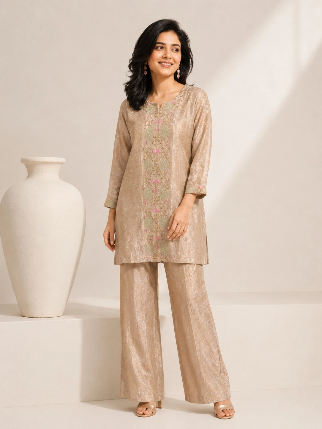 Woman wearing a shimmering grey embroidered kurta and matching pants, styled for a festive occasion.