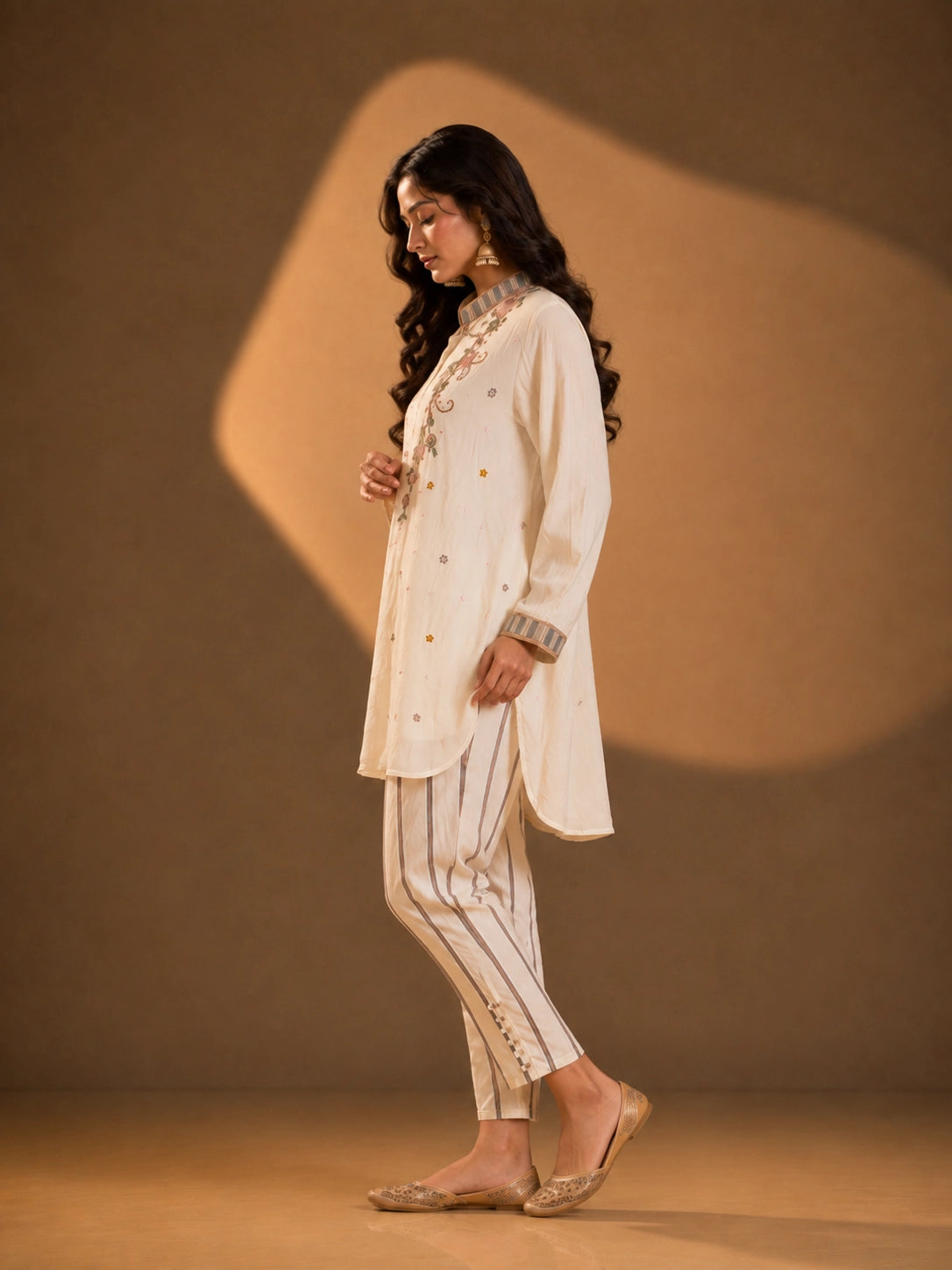 Woman wearing an elegant cream embroidered button-down kurti with striped collar and cuffs.