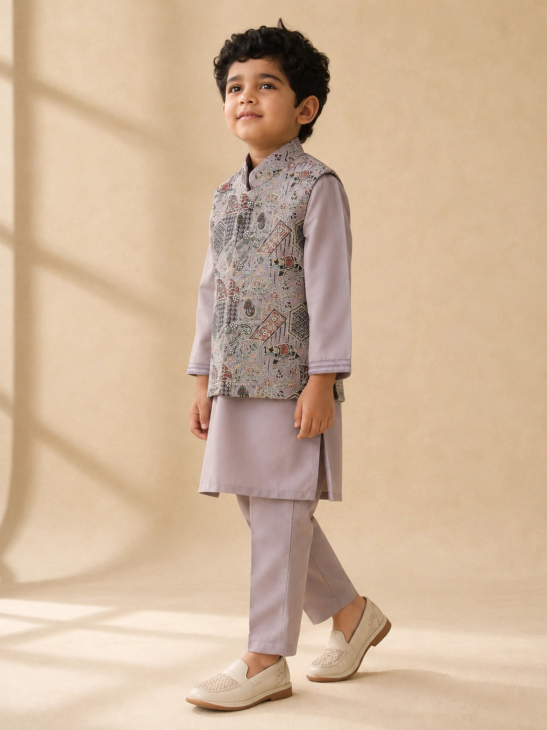 Young boy wearing a levendar kurta pajama with an intricately patterned waistcoat.