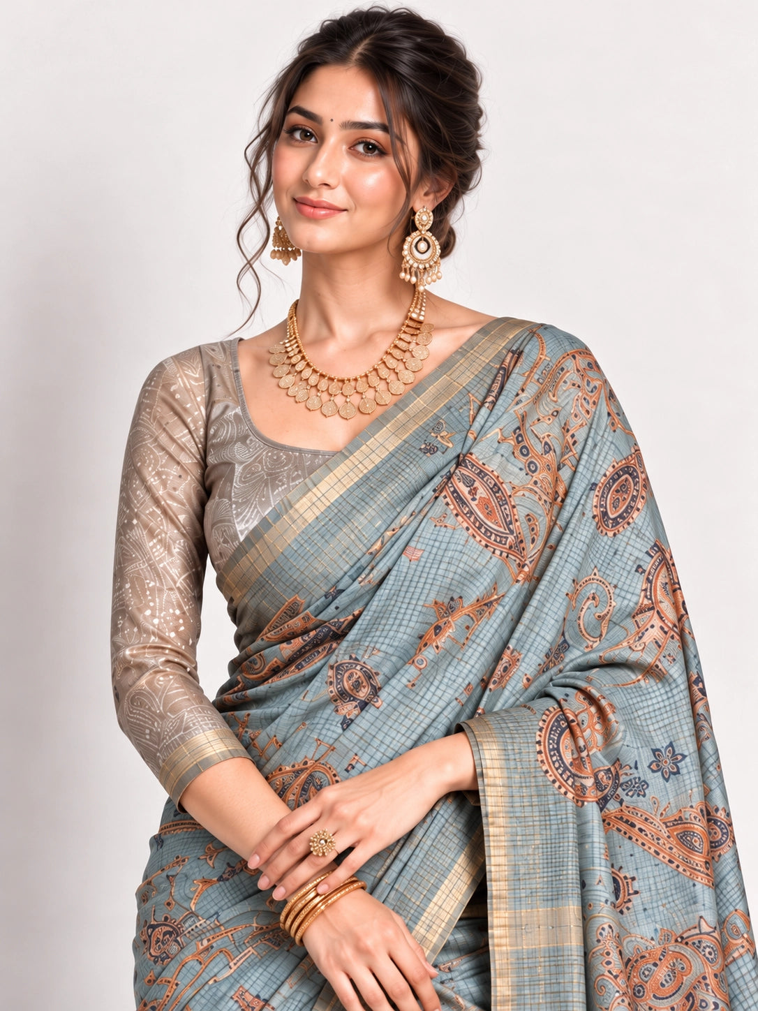 Woman in an elegant lavender grey saree with gold border and intricate paisley patterns.