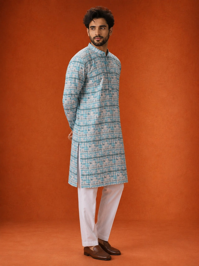 Man wearing an aqua and white printed kurta with white pajamas and brown loafers.