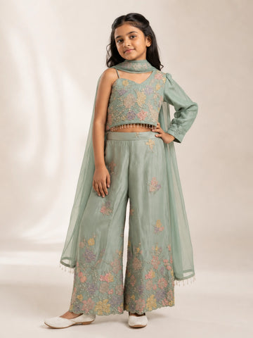 Young girl wearing a green embroidered one-shoulder palazzo set with a matching dupatta.
