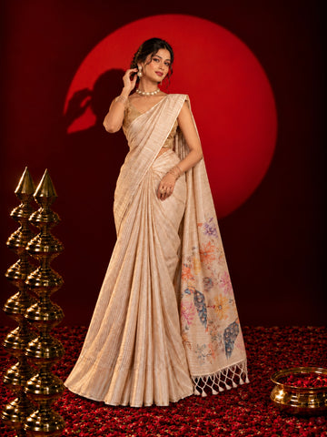 Woman in an elegant beige saree with floral and peacock pallu design.
