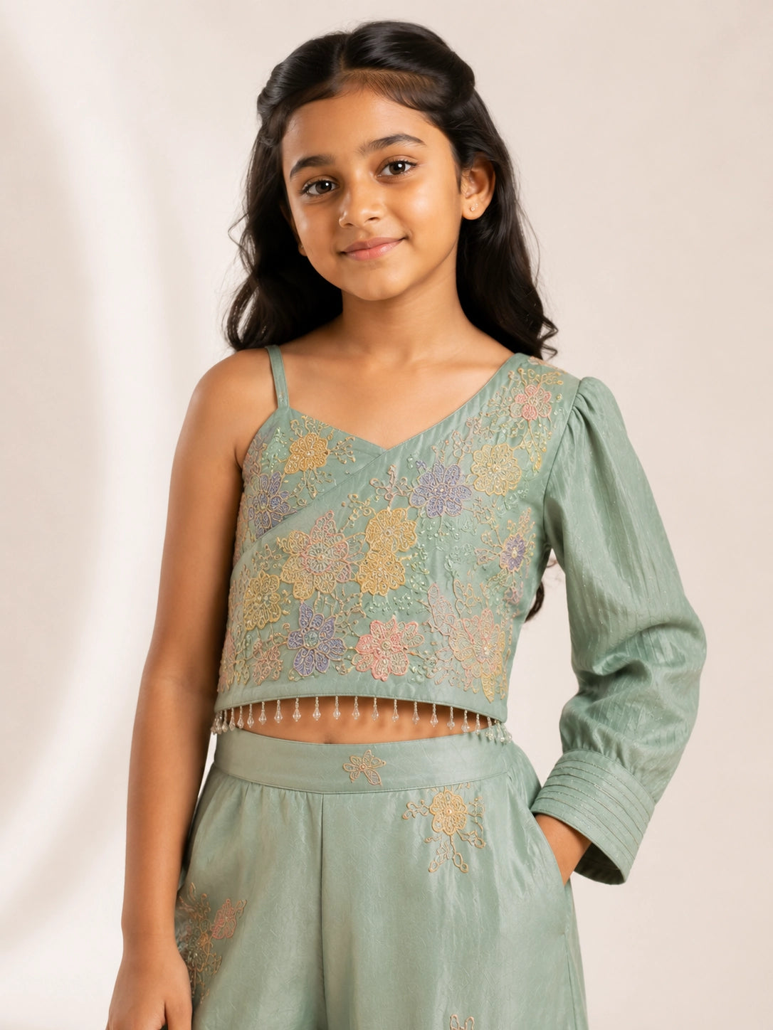 Young girl wearing a green embroidered one-shoulder palazzo set with a matching dupatta.